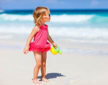 Kind am Strand mit Giesskanne