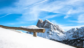 Verschneite Bergwelt in Tirol mit Holzbank
